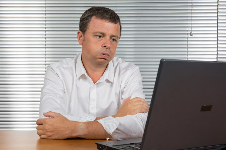 frustrated man at office looking at his system - Clearing Your Criminal Record Starts by Understanding Record Suspensions in Canada